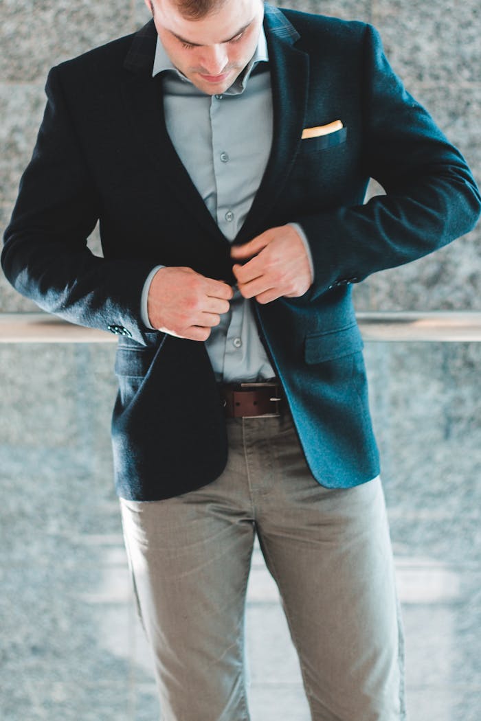 Close-up of a man adjusting his suit jacket indoors, showcasing elegant style and formal wear.